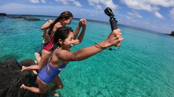 três mulheres se divertindo na praia com uma GoPro na mão