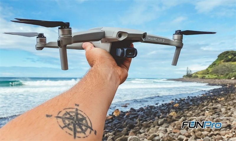 Pessoa segurando drone na mão esquerda na praia