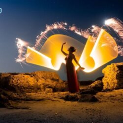 mulher de vestido vermelho fazendo light painting no deserto de noite