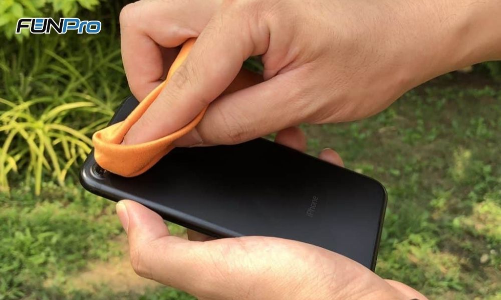 limpando lente da câmera traseira de um iphone preto com paninho laranja